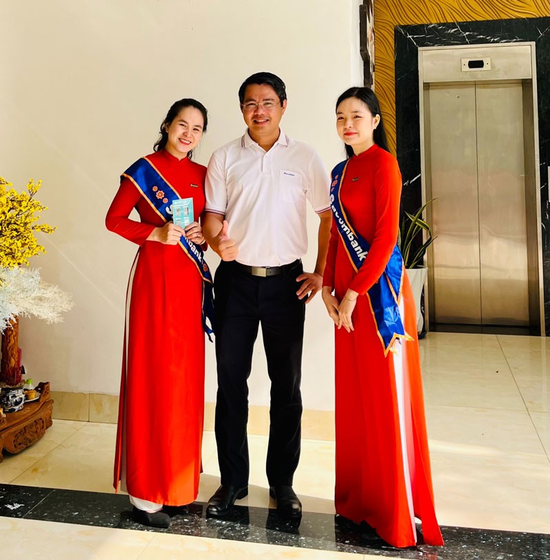 Áo dài đồng phục Sacombank màu cam nổi bật, thể hiện nét đẹp truyền thống và chuyên nghiệp của nữ nhân viên