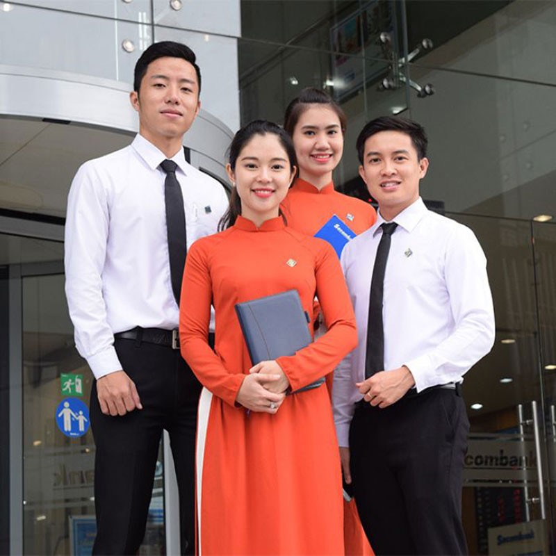 Đồng phục sơ mi Sacombank với mẫu nữ màu cam và mẫu nam màu trắng, phù hợp cho công việc hàng ngày